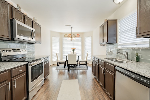 kitchen with visible vents, a sink, appliances with stainless steel finishes, dark brown cabinets, and dark wood-style flooring