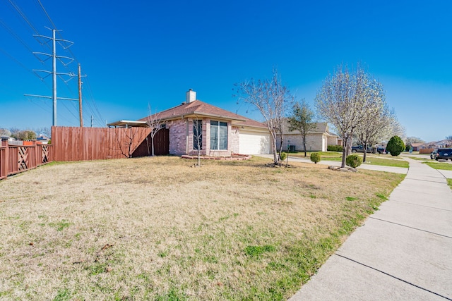 view of home's exterior featuring fence, a yard, an attached garage, a chimney, and brick siding