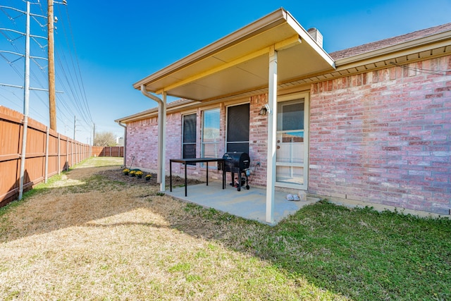 exterior space featuring brick siding, a patio, and fence