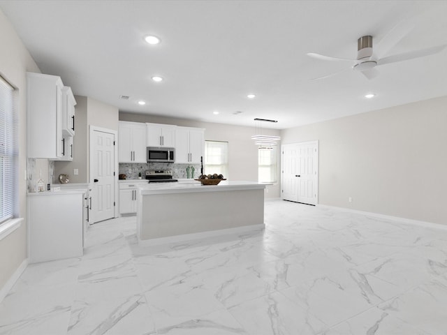 kitchen with white cabinets, stainless steel appliances, baseboards, recessed lighting, and a kitchen island