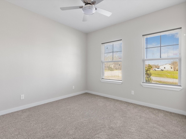 carpeted spare room featuring baseboards and ceiling fan