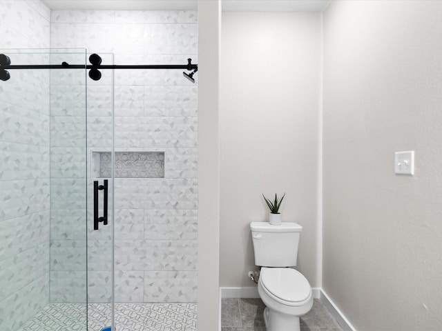 bathroom with a shower stall, toilet, tile patterned flooring, and baseboards