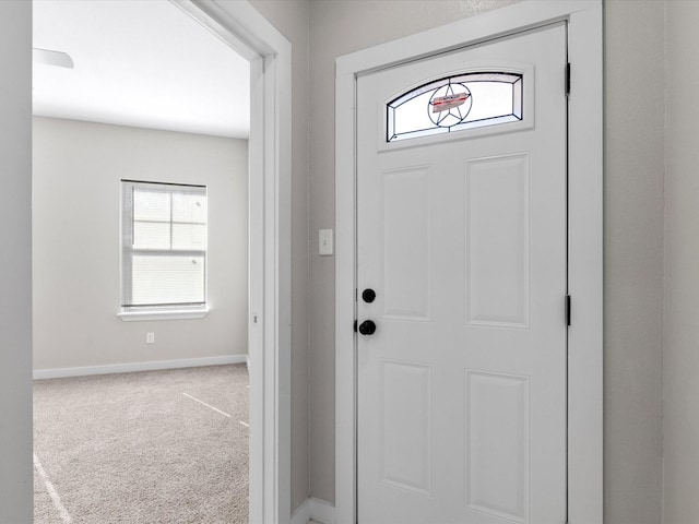 carpeted foyer featuring baseboards