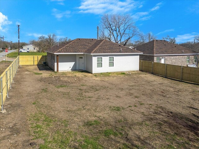 rear view of property with a fenced backyard and roof with shingles