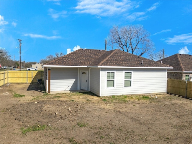 rear view of property featuring a fenced backyard and a shingled roof