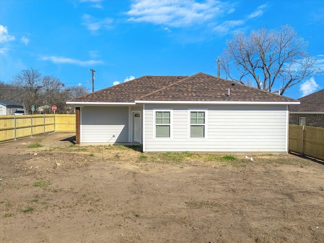 rear view of property with a shingled roof and a fenced backyard