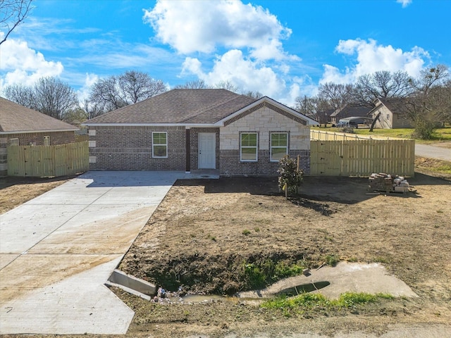 view of front of home with fence, a shingled roof, driveway, and a gate