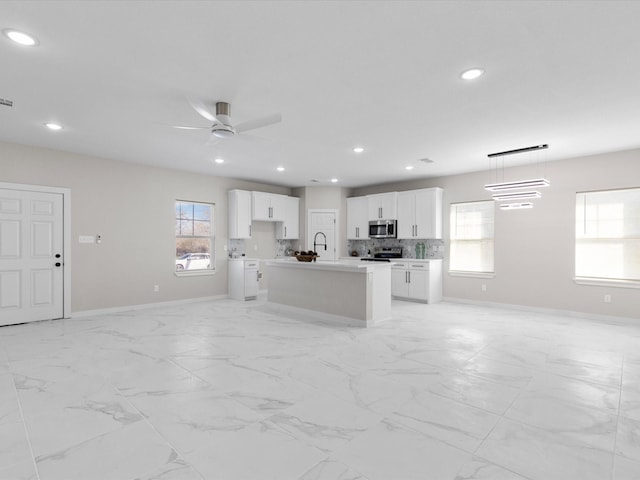 kitchen featuring open floor plan, baseboards, appliances with stainless steel finishes, and plenty of natural light