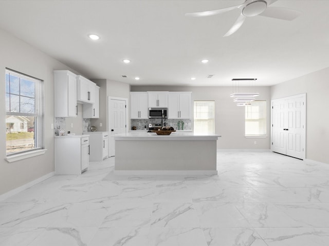 kitchen with stainless steel microwave, baseboards, white cabinetry, and recessed lighting