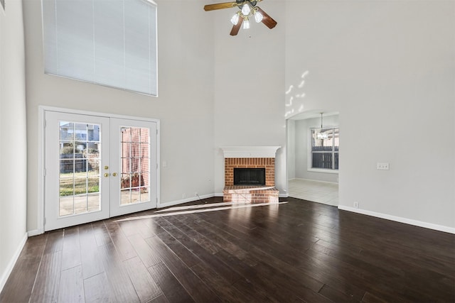 unfurnished living room featuring a fireplace, baseboards, french doors, and wood finished floors