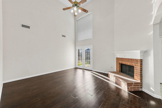 unfurnished living room featuring visible vents, wood finished floors, french doors, baseboards, and a brick fireplace