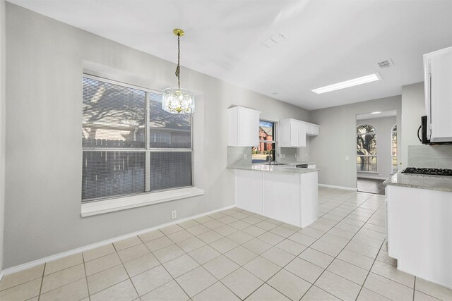 kitchen with light tile patterned floors, a peninsula, a sink, decorative backsplash, and white cabinetry