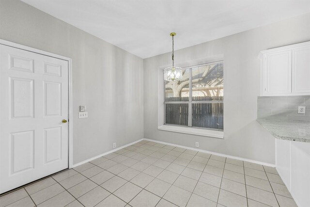 unfurnished dining area with light tile patterned floors, baseboards, and a chandelier