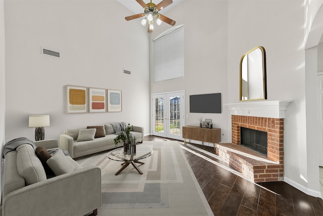 living room with wood finished floors, visible vents, baseboards, french doors, and a brick fireplace