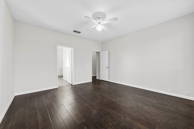 empty room featuring ceiling fan, visible vents, baseboards, and dark wood finished floors