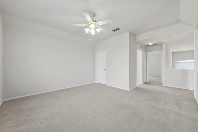 spare room with visible vents, lofted ceiling, a ceiling fan, baseboards, and light colored carpet