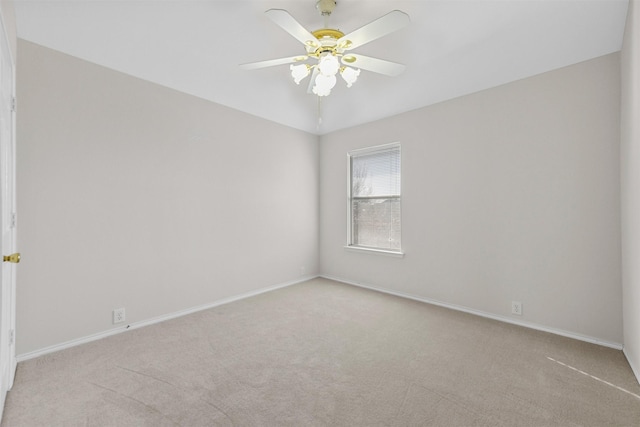 carpeted spare room featuring baseboards and ceiling fan