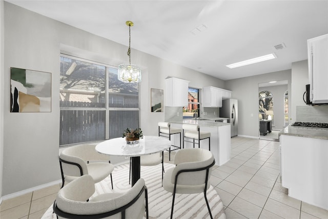 dining area with light tile patterned floors, visible vents, a healthy amount of sunlight, and a chandelier