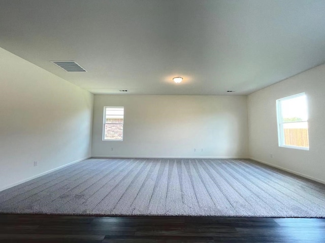 unfurnished room featuring wood finished floors, baseboards, and visible vents