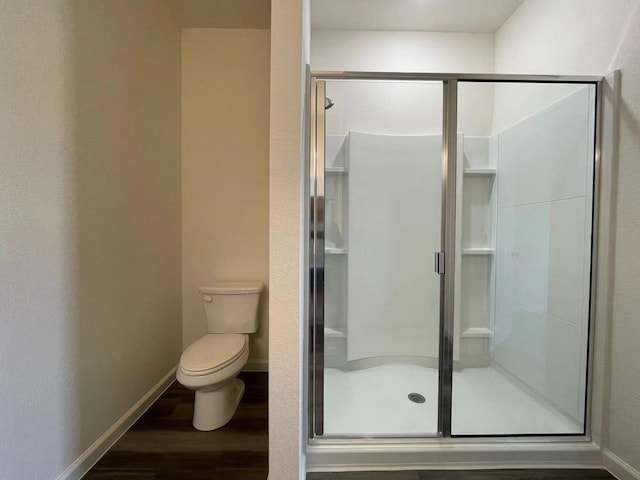 full bathroom featuring a shower stall, toilet, baseboards, and wood finished floors