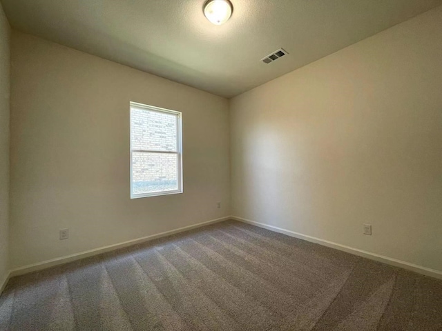 spare room with baseboards, visible vents, and carpet floors