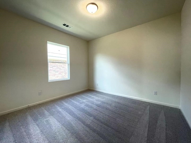 empty room with baseboards, visible vents, and dark colored carpet