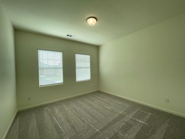 carpeted spare room featuring visible vents and baseboards