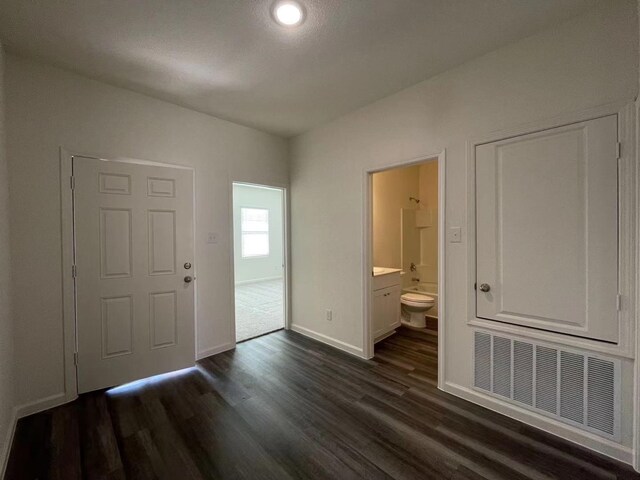 foyer entrance with dark wood finished floors, visible vents, and baseboards