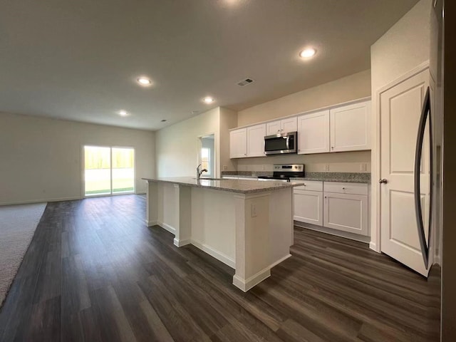 kitchen with light stone counters, a sink, dark wood-type flooring, white cabinets, and appliances with stainless steel finishes