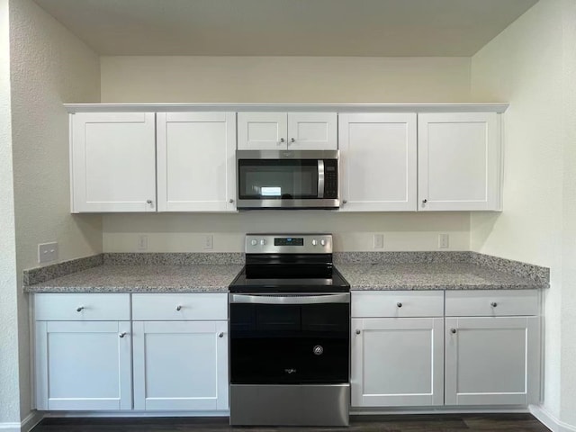 kitchen featuring light stone counters, appliances with stainless steel finishes, and white cabinetry