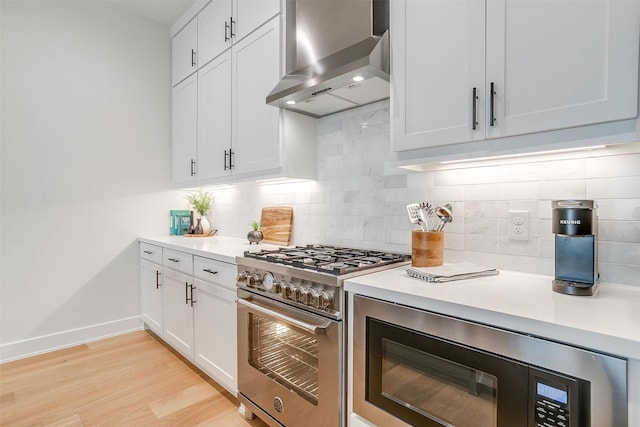 kitchen with high end stove, light wood-style floors, wall chimney exhaust hood, light countertops, and built in microwave