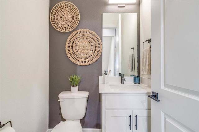 half bath with toilet, vanity, and a textured wall