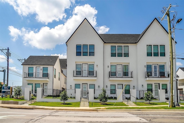 townhome / multi-family property with a fenced front yard and stucco siding