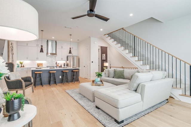 living area with visible vents, recessed lighting, light wood-type flooring, and stairs