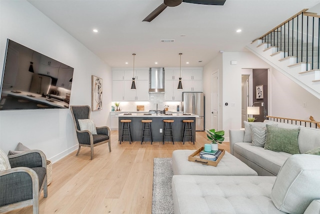 living area with visible vents, light wood-style flooring, recessed lighting, ceiling fan, and stairs