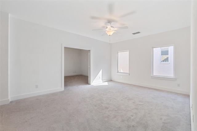 unfurnished room featuring visible vents, baseboards, light colored carpet, and a ceiling fan