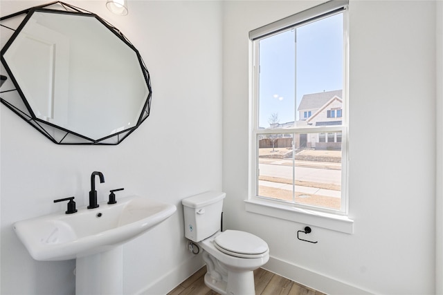 bathroom with a sink, toilet, baseboards, and wood finished floors