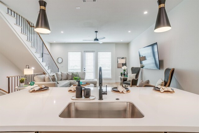 kitchen with open floor plan, pendant lighting, light countertops, and a sink