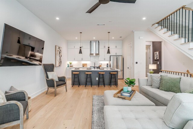 living room featuring visible vents, ceiling fan, stairway, light wood-type flooring, and recessed lighting