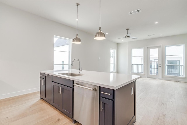 kitchen featuring visible vents, a sink, light wood-style floors, dishwasher, and decorative light fixtures