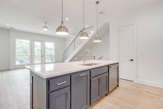 kitchen featuring dishwasher, gray cabinetry, light wood finished floors, and a sink