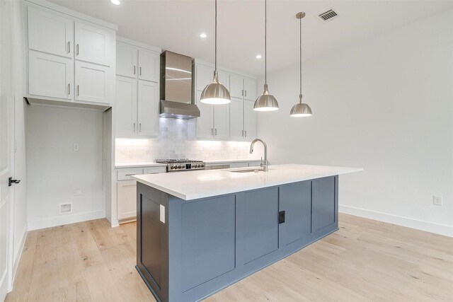 kitchen with light wood-style flooring, a sink, wall chimney range hood, range, and backsplash