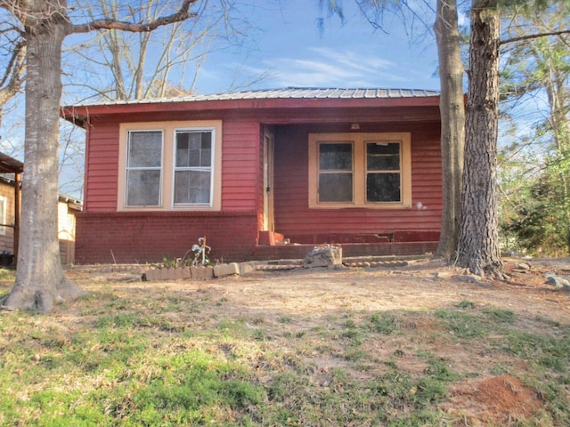 view of front of home featuring brick siding and metal roof