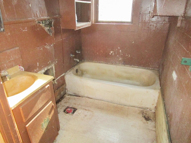 bathroom with a bathing tub, vanity, and tile walls