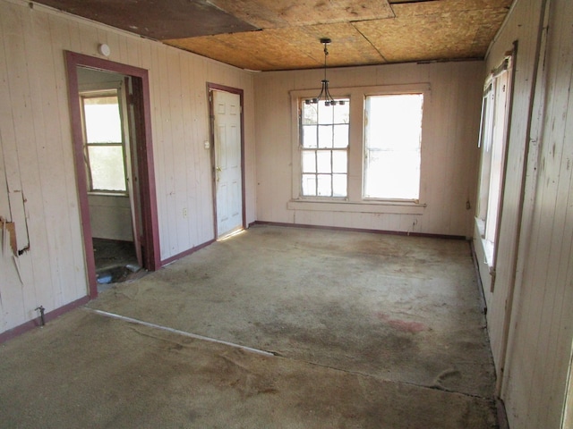 unfurnished dining area featuring wooden walls and baseboards