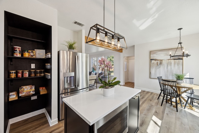 kitchen with visible vents, stainless steel fridge with ice dispenser, built in microwave, light wood-type flooring, and a notable chandelier