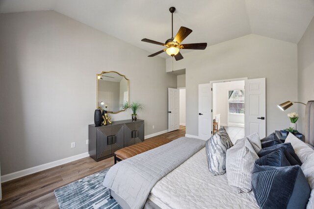 bedroom with vaulted ceiling, wood finished floors, and baseboards