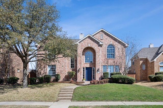 traditional-style home with brick siding, a chimney, and a front lawn