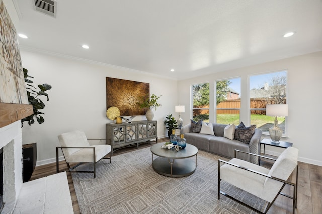 living area with a fireplace, wood finished floors, visible vents, and baseboards