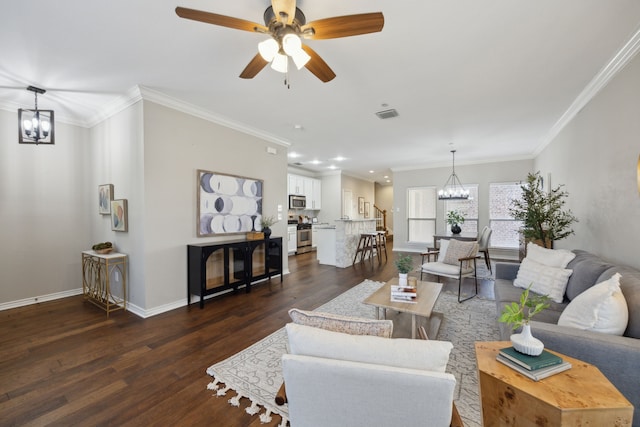 living area with baseboards, visible vents, dark wood-type flooring, crown molding, and ceiling fan with notable chandelier